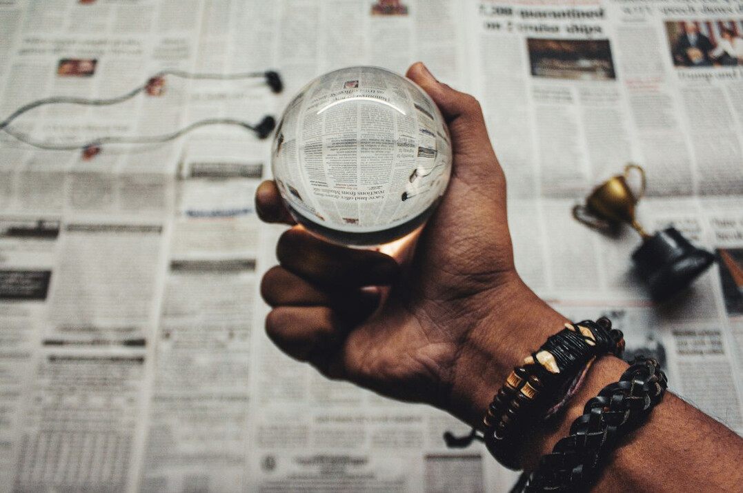 Magnifying glass held over a printed newspaper article